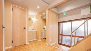 A hallway with wooden flooring, a kitchen area, and a staircase leading to an upper floor. - skytree Family Hotel (Tokyo)