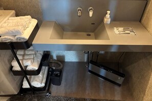 Une salle de bain moderne dotée d’un lavabo intégré, d’un porte-serviettes et de toilettes.