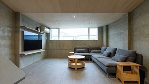 Una sala de estar moderna con un sofá grande, un televisor montado en la pared y una mesita de madera.