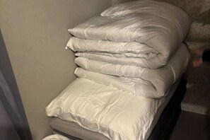 Une pile de linge de lit blanc sur un lit.