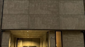 Un edificio con fachada de hormigón, un acceso cubierto y un coche estacionado en el interior.