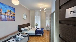A modern bedroom with a bed, a nightstand, a lamp, a painting, and a sign reading "STUDIO A". - Old Town KRAKÓW STUDIO  (Kraków)