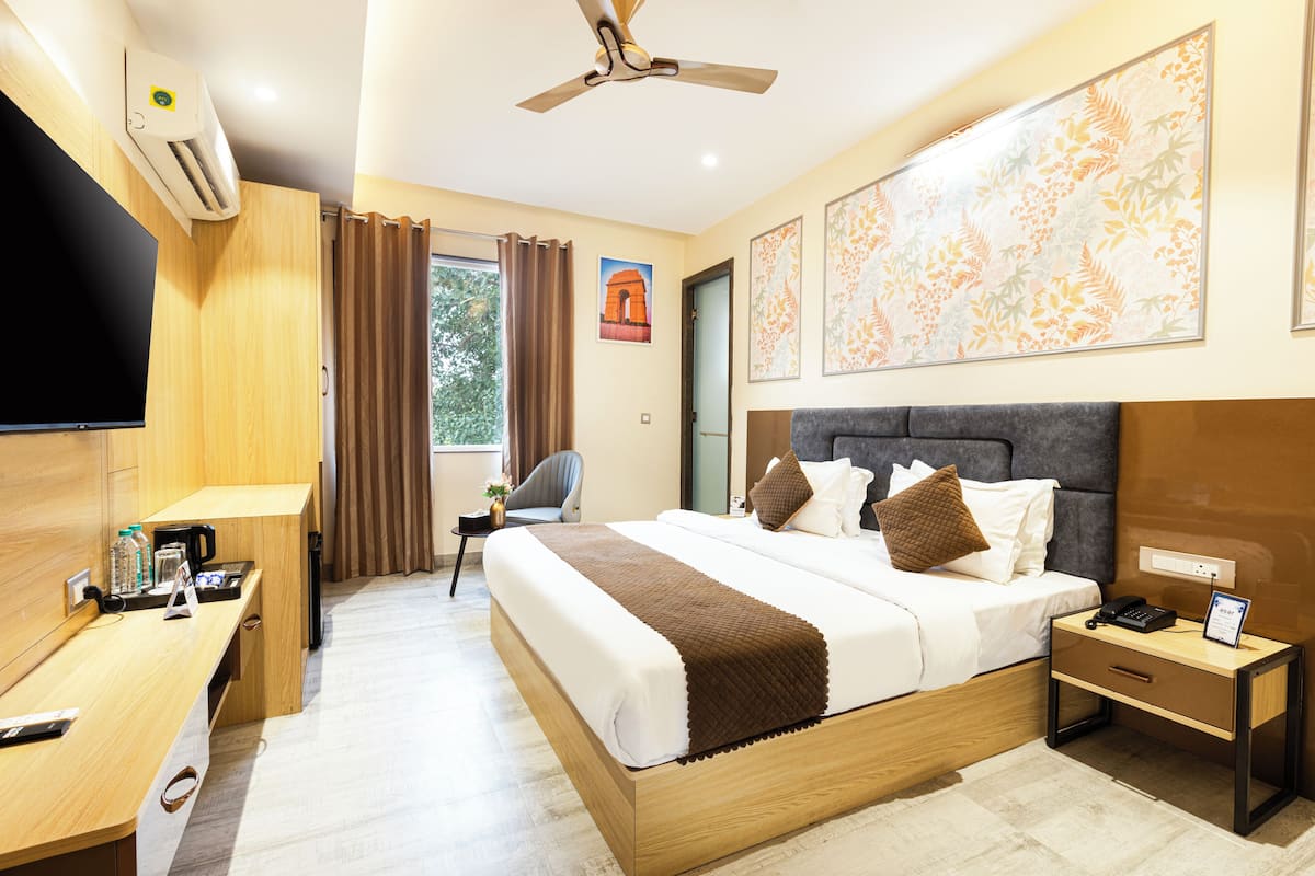 Habitació d'hotel amb llit, taula de nit, escriptori, cadira i obra d'art a les parets.