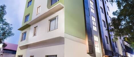 Un edificio de varios pisos con fachada verde y blanca, múltiples ventanas y un letrero que dice "asari".