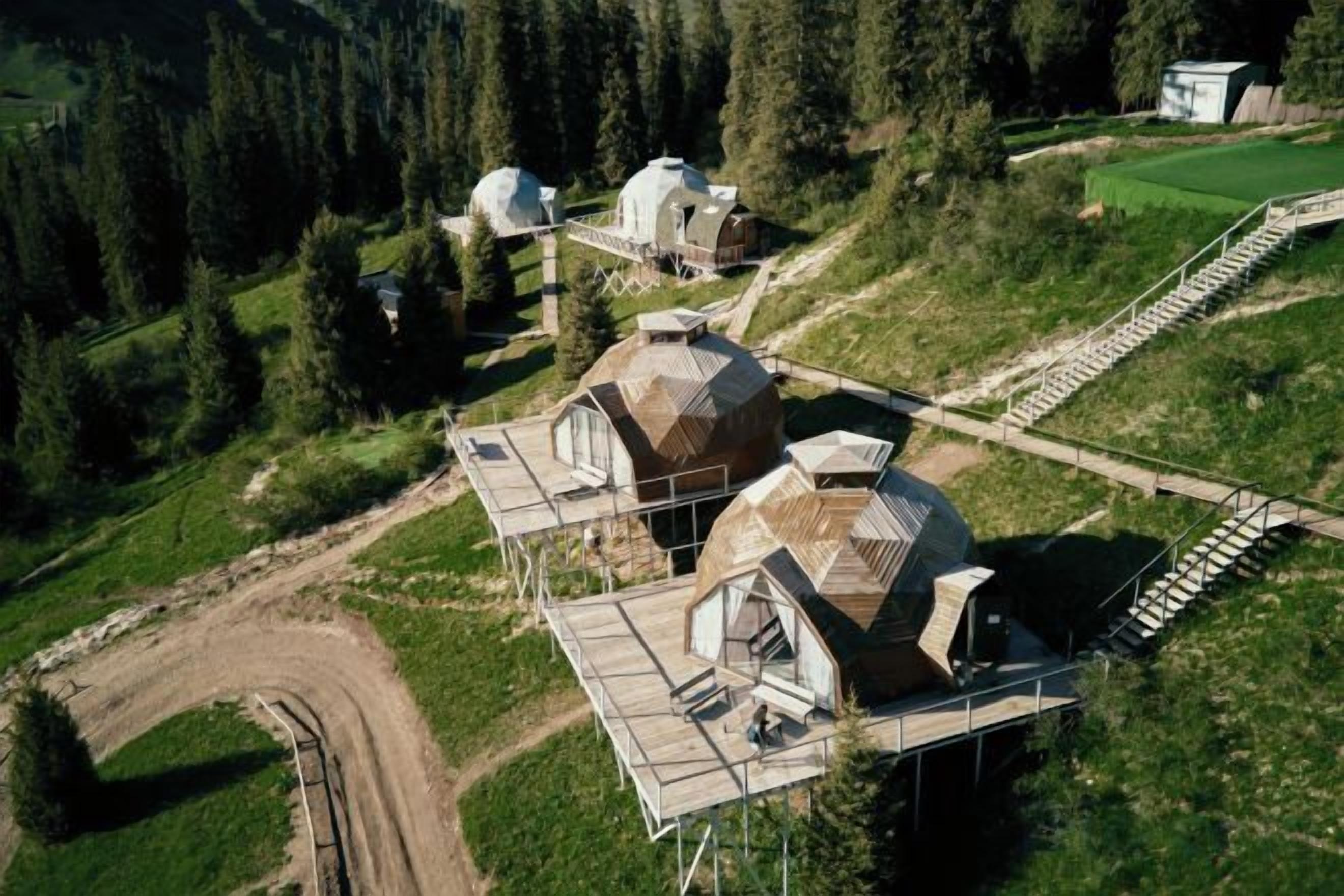 Complejo con varias estructuras abovedadas, un sendero de tierra y un pequeño edificio en zona boscosa.