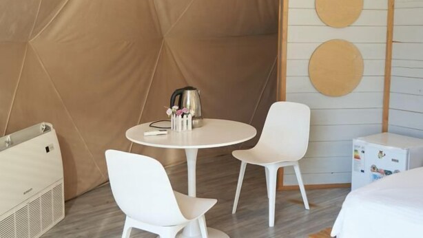 A modern room with a round table, two white chairs, a bed, a heater, and a wall with circular decorations. - Pana Nomad Kolsay (Kegen)