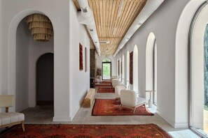 A hallway with a red carpet, white walls, and arched windows. - Pana Nomad Kolsay (Kegen)