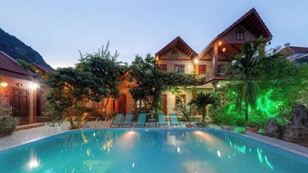 A poolside view of a resort with a swimming pool, lounge chairs, and a building with a balcony.