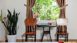 A room with two wooden chairs, a small table, and a potted plant.