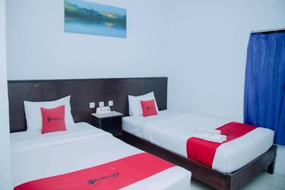 A hotel room with two beds, a nightstand with a phone, and a painting on the wall.