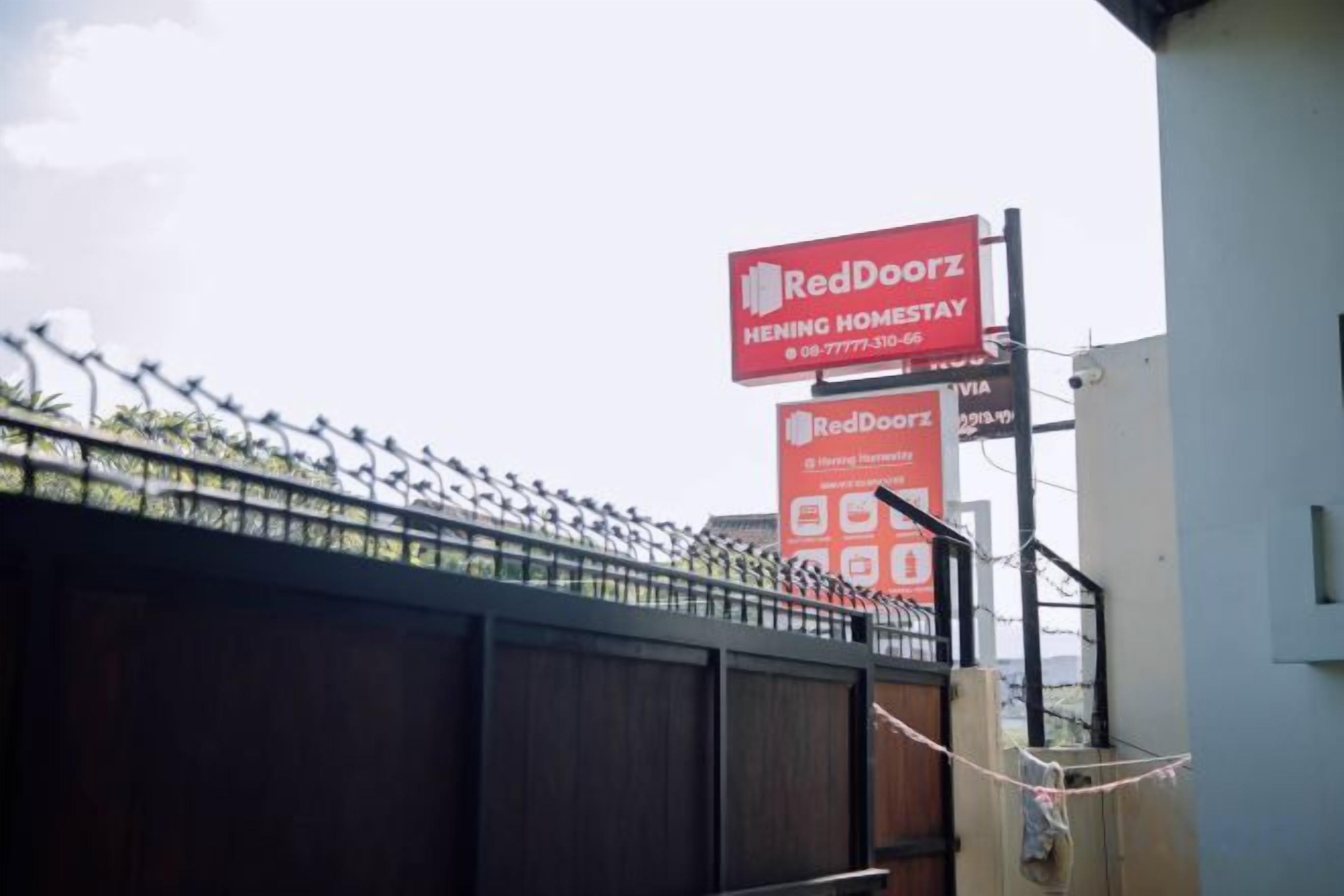 A RedDoorz Hening Homestay sign with contact information.