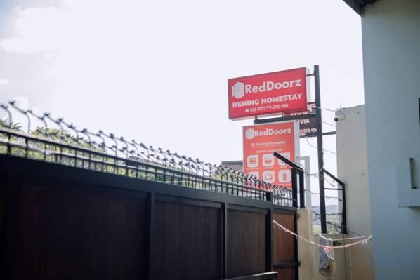 Une enseigne RedDoorz Hening Homestay avec les coordonnées.