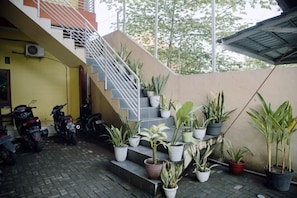 Un escalier menant à un deuxième étage, bordé de plantes en pot et de motos garées.