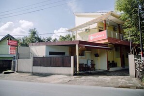 Un immeuble de deux étages avec une enseigne rouge portant l’inscription « RedDoorz » au rez-de-chaussée.