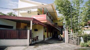 A two-story building with a red and yellow facade, a covered entrance, and a gated driveway.
