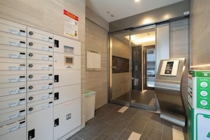Eine Hotelhalle mit einer Reihe von Schließfächern, einem Glastunnel und einem Automaten.