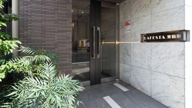 A building entrance with a glass door, a sign reading "LA FESTA," and a tiled wall. - LAFESTA Higashi Komagata　 (Tokyo)