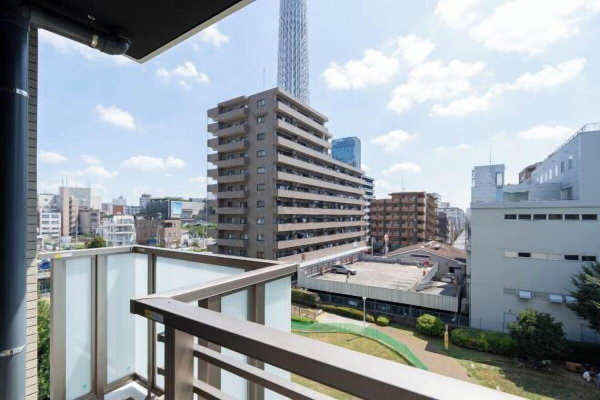 Un edificio de gran altura con varios pisos, un estacionamiento y un pequeño espacio verde.
