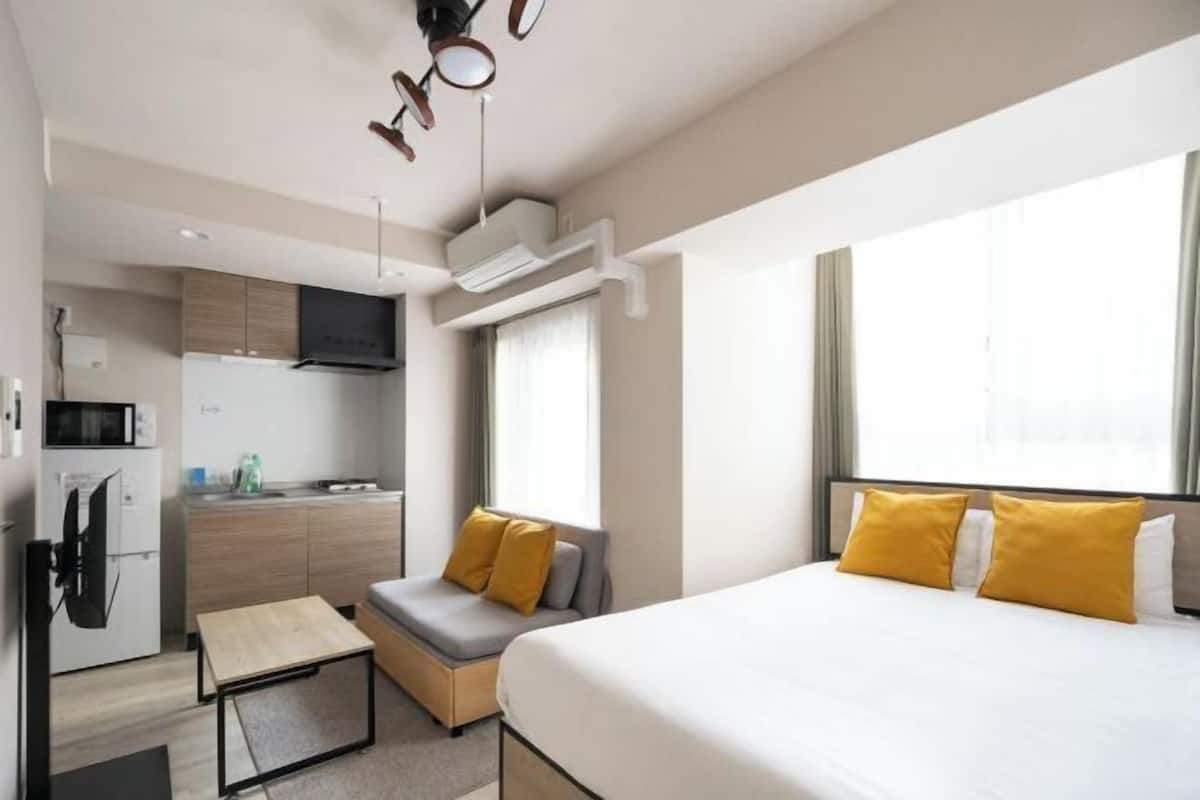Una habitación de hotel compacta con cama, kitchenette pequeña y zona de estar.