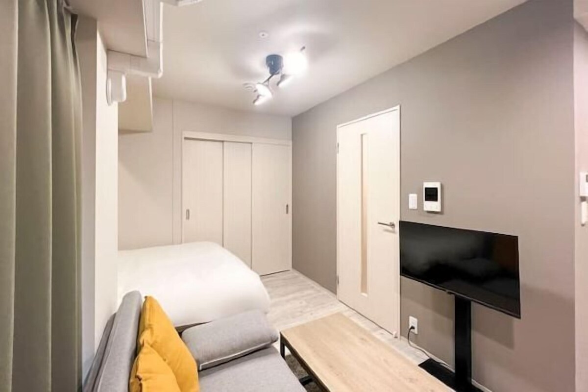 A modern hotel room with a bed, a TV, and a desk.