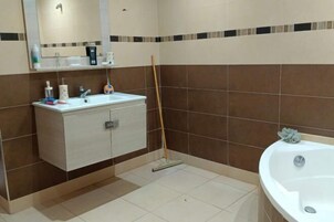 Un baño con lavamanos, espejo y bañera blancos.