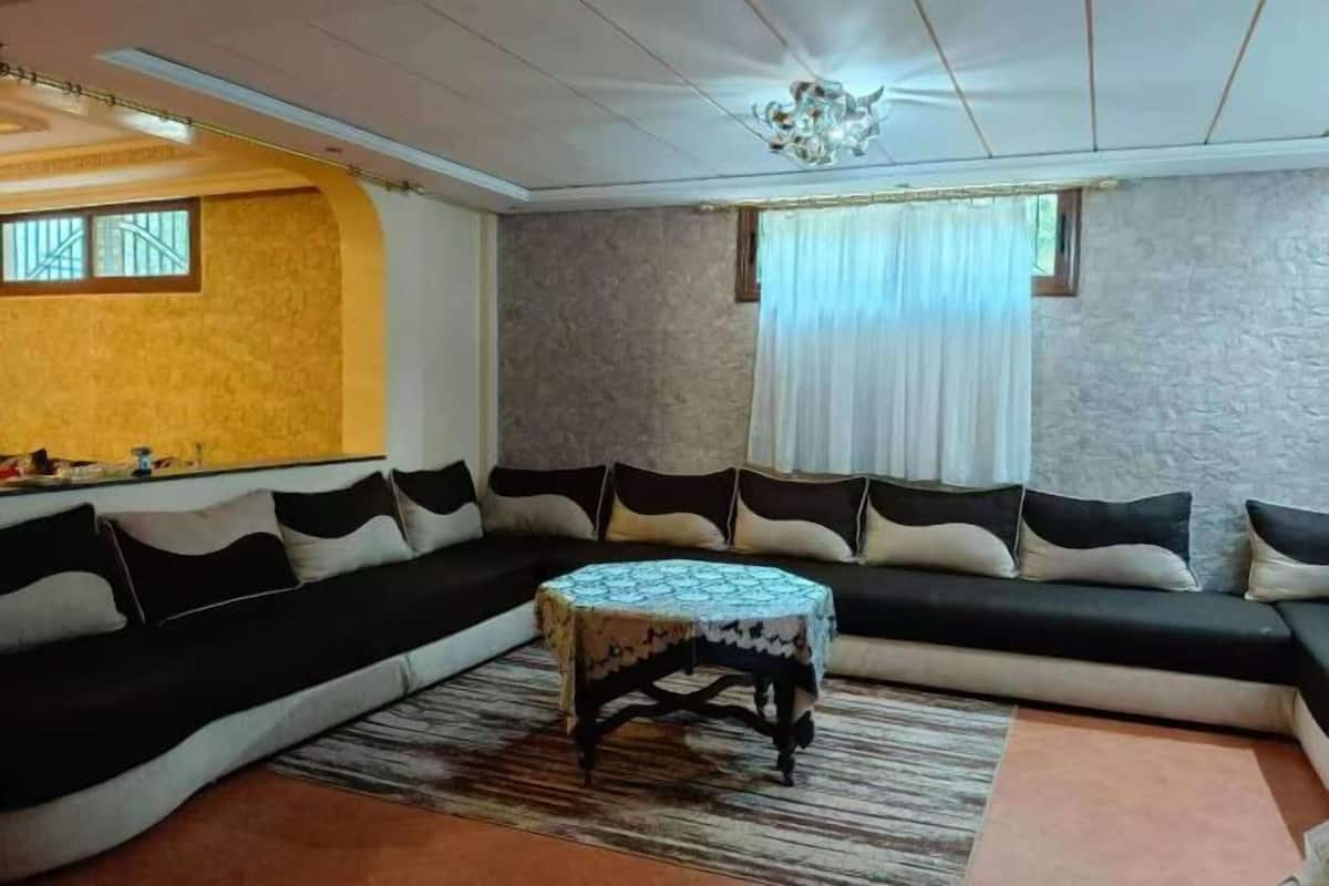 A living room with a sectional sofa, a round coffee table, and a chandelier.