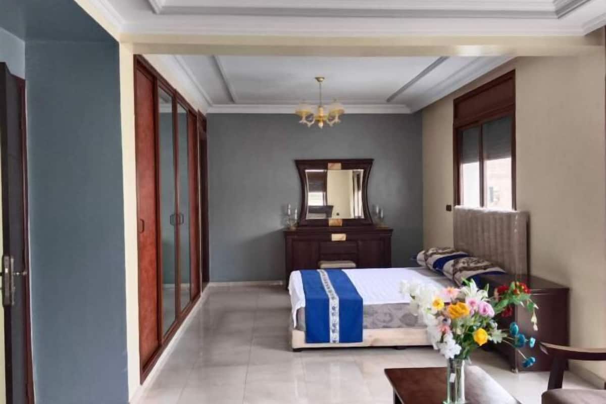 A bedroom with a bed, dresser, mirror, and a vase with flowers.