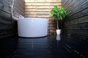 Une salle de bain moderne avec une grande baignoire blanche, une plante en pot et des murs en bois.