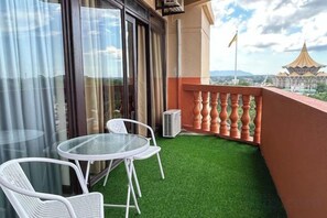 A balcony with artificial grass, two white chairs, and a glass table. - Highfloor Riverbank Suites level 12 (Kuching)