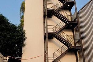 Un edificio de varios pisos con escaleras exteriores y fachada de metal corrugado.