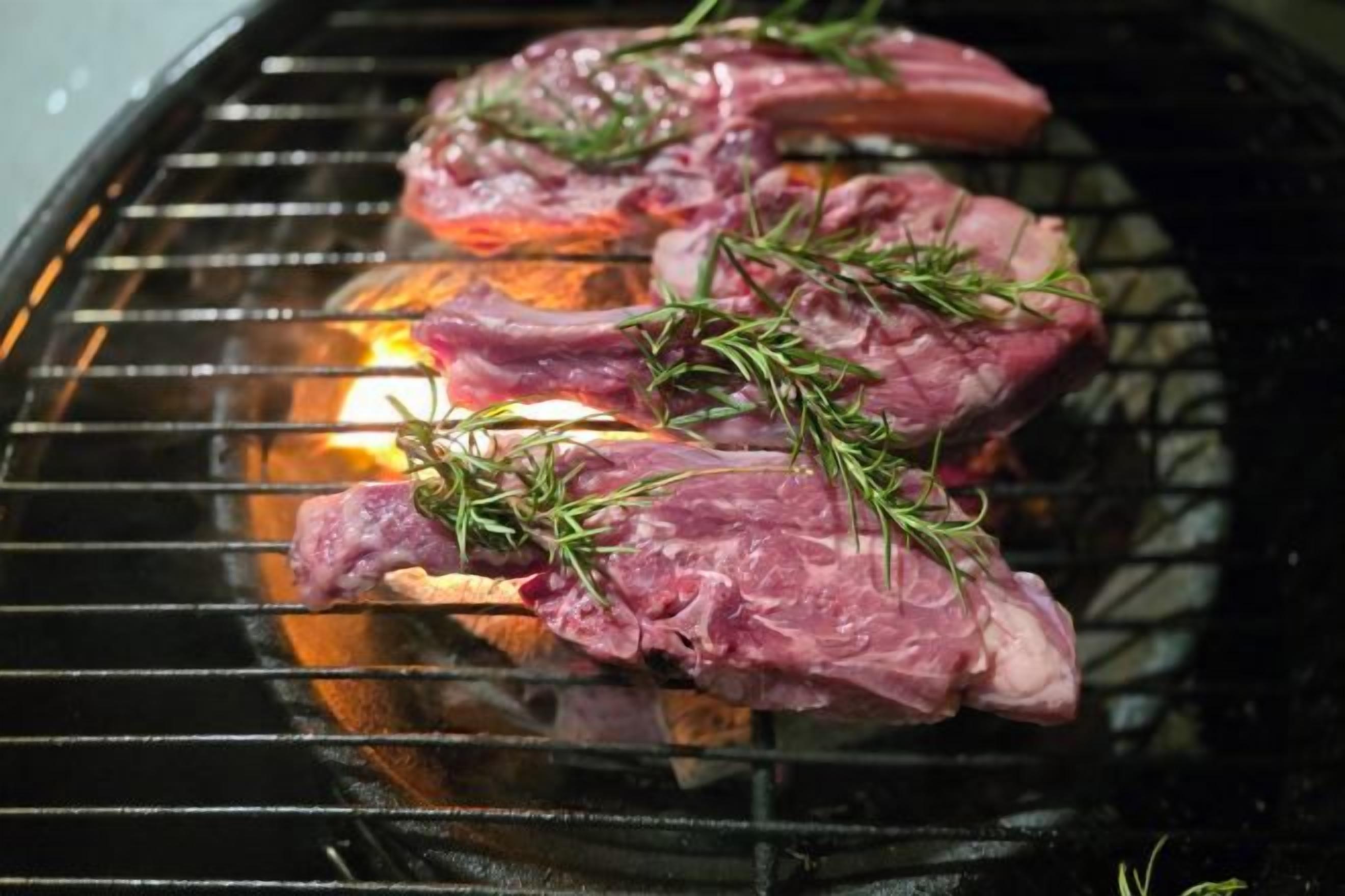 Carne cruda en una parrilla con hierbas.