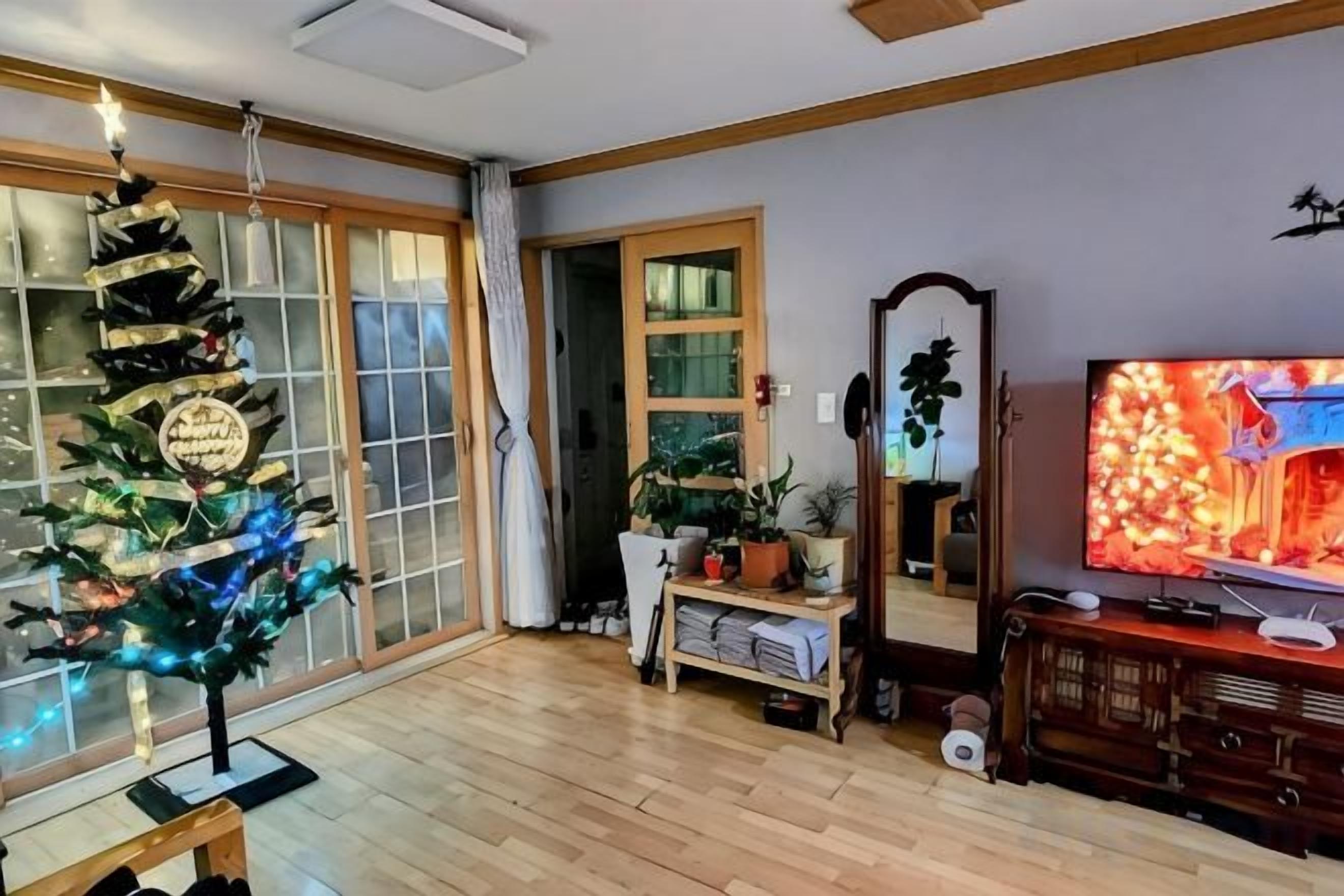 Una sala de estar con un árbol de Navidad, un televisor y un espejo.
