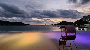 En vy över stranden med en stol och ett poolområde.