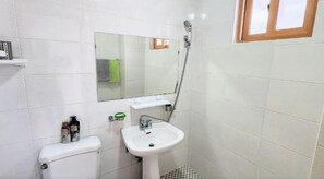 A small, clean bathroom with white tiles, a toilet, a sink, a mirror, and a shower. - Ha-Wahyeon HOUSE: Great location, views and vibe! (Geoje-si)