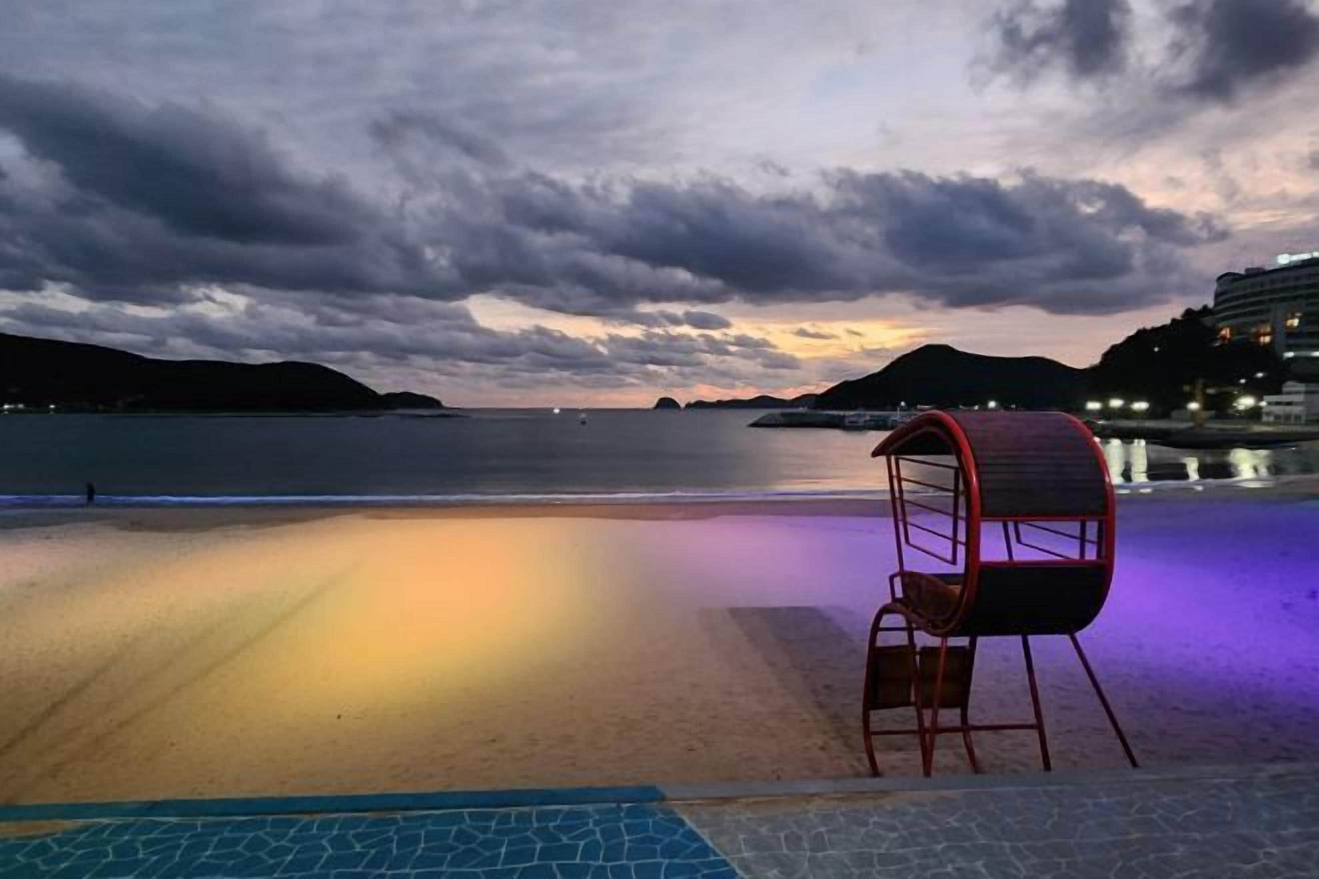 A beach with a chair and a poolside area.