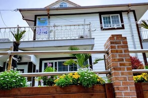 A two-story building with a balcony, a brick chimney, and flower boxes with various plants. - Ha-Wahyeon HOUSE: Great location, views and vibe! (Geoje-si)