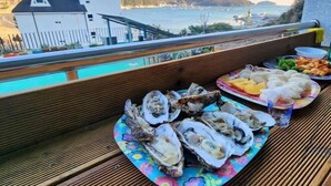 En balkong med utsikt över havet, en pool och ett bord med mat på.