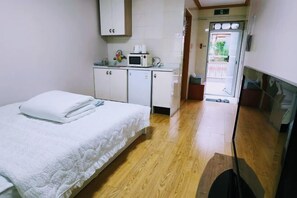 A hotel room with a bed, a kitchenette with a microwave, and a wooden floor. - Ha-Wahyeon HOUSE: Great location, views and vibe! (Geoje-si)