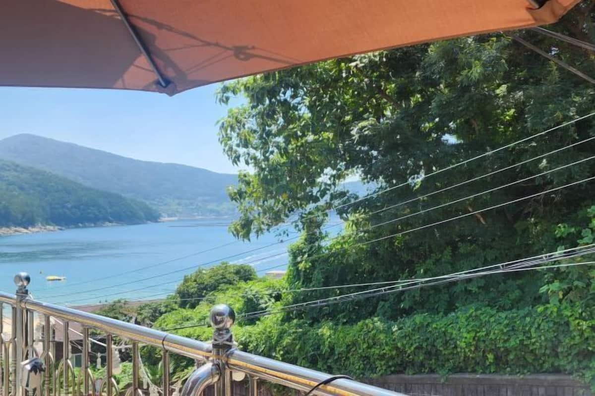A balcony with a metal railing, overlooking a body of water and greenery.