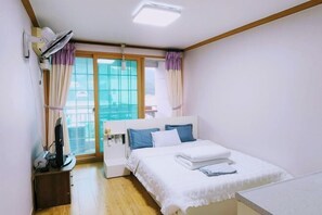 A bedroom with a bed, a desk with a computer, a window with curtains, and a ceiling fan. - Ha-Wahyeon HOUSE: Great location, views and vibe! (Geoje-si)