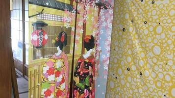 Una habitación tradicional japonesa con suelo de tatami, un mamparo shoji y decoración temática de cerezo.