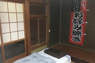 Una habitación japonesa tradicional con suelo de tatami, puertas correderas shoji y una cama futón.