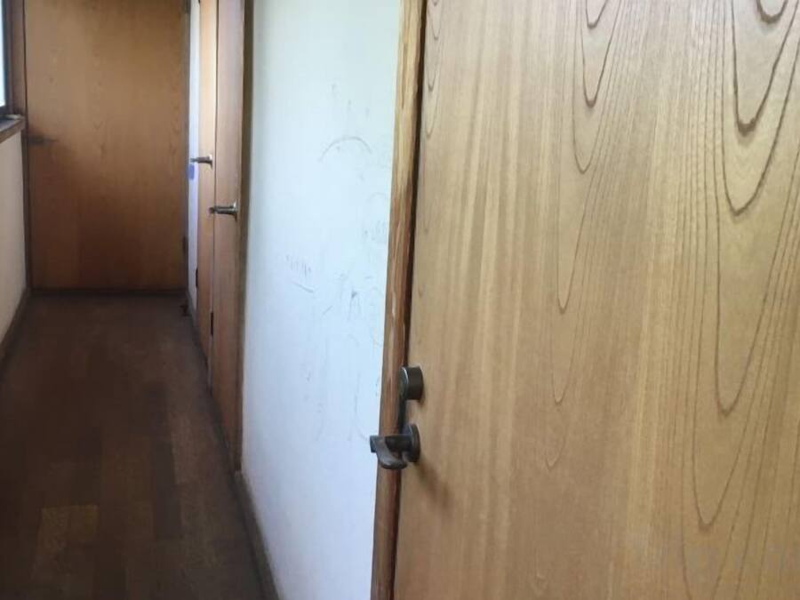 A narrow hallway with wooden doors and a wooden floor.