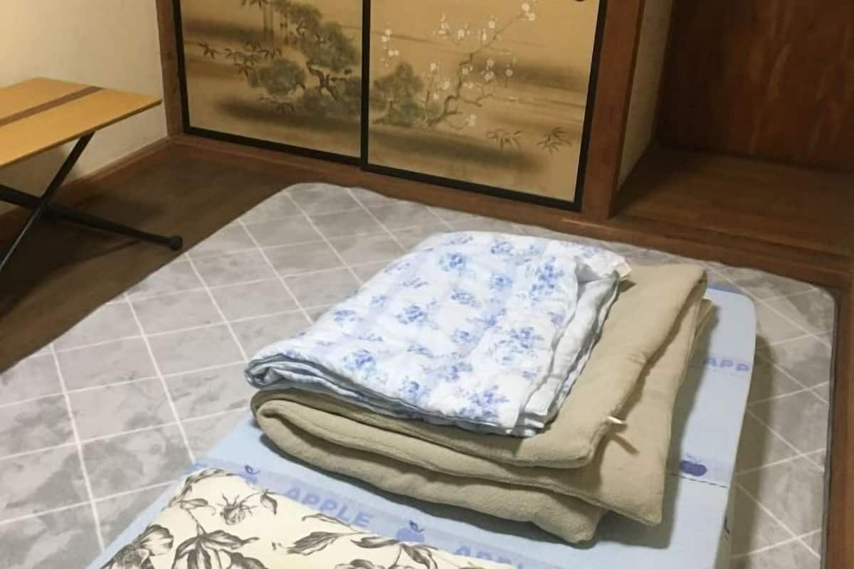 Ein Zimmer mit einem Bett, einem Holztisch und einer Wand mit traditioneller Kunst.