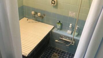 A bathroom with a shower, toilet, and hand sanitizer dispenser.