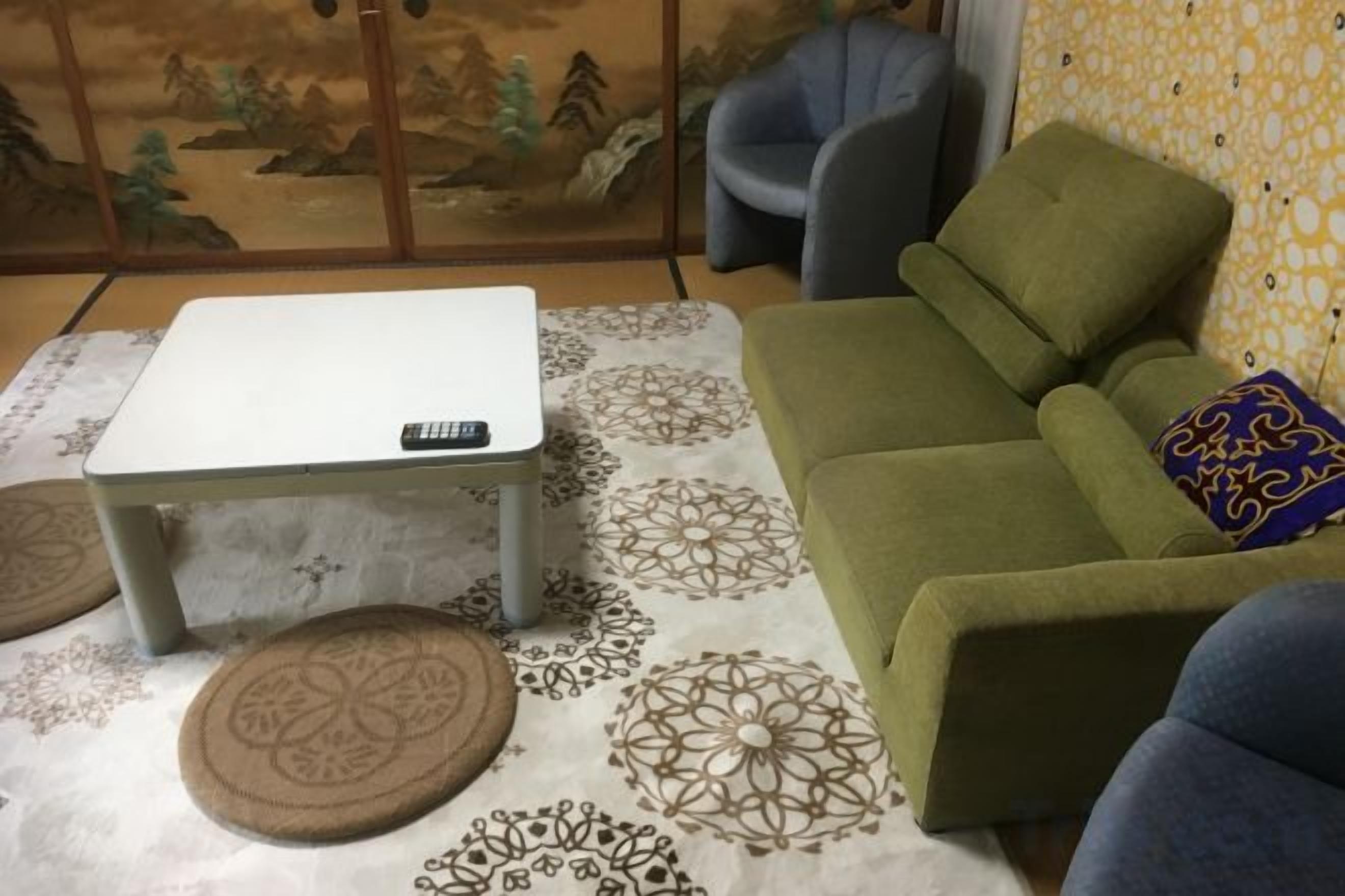 Een kamer met een bank, een klein tafeltje en een kamerkleed met een patroon.