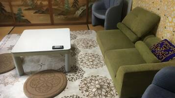 Een kamer met een bank, een klein tafeltje en een kamerkleed met een patroon.