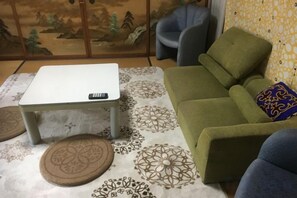 Een kamer met een bank, een klein tafeltje en een kamerkleed met een patroon.