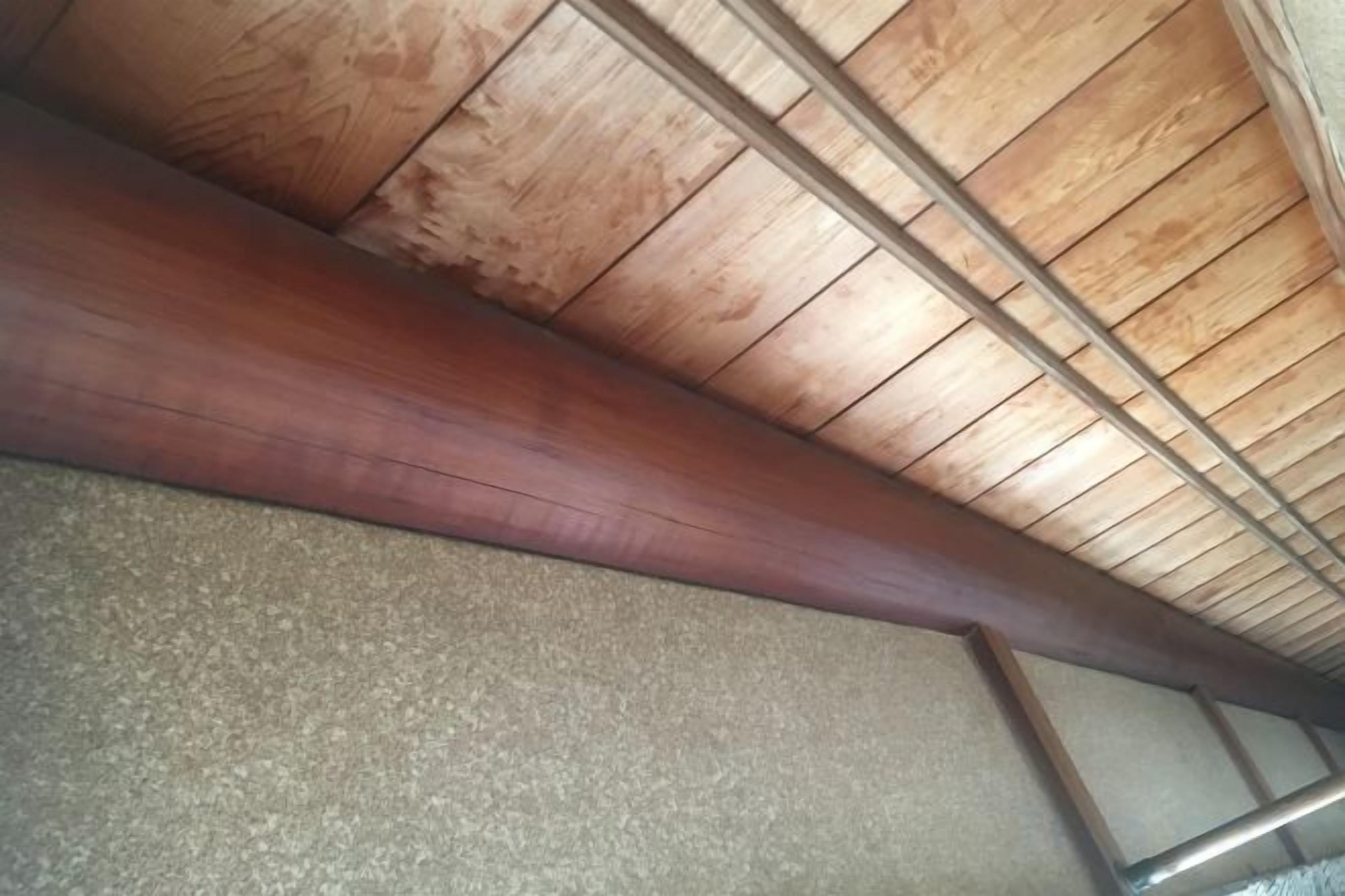 Techo de madera con vigas a la vista y piso con textura.