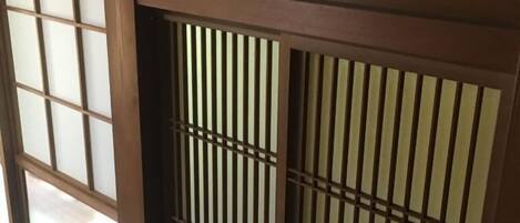 Ein traditioneller japanischer Shoji-Schirm mit vertikalen Lamellen und einem Gittermuster im oberen Bereich.